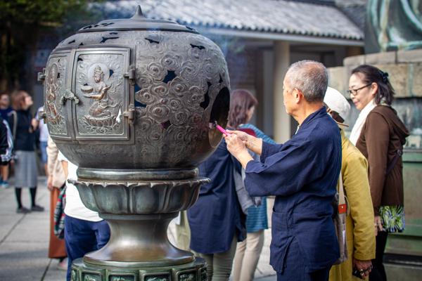 An older man is lighting a brazier. There were many such locations throughout the temple.