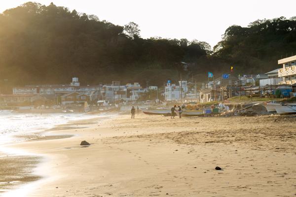 Folks spread across Yuigahama Beach in Kamakura near sunset.